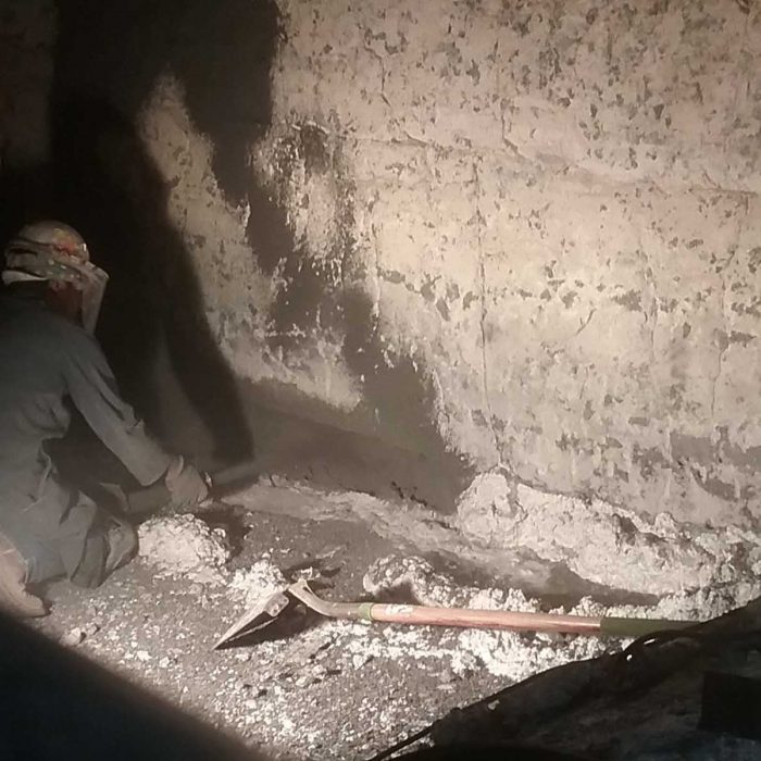 a worker aims what appears to be a hose at a concrete wall